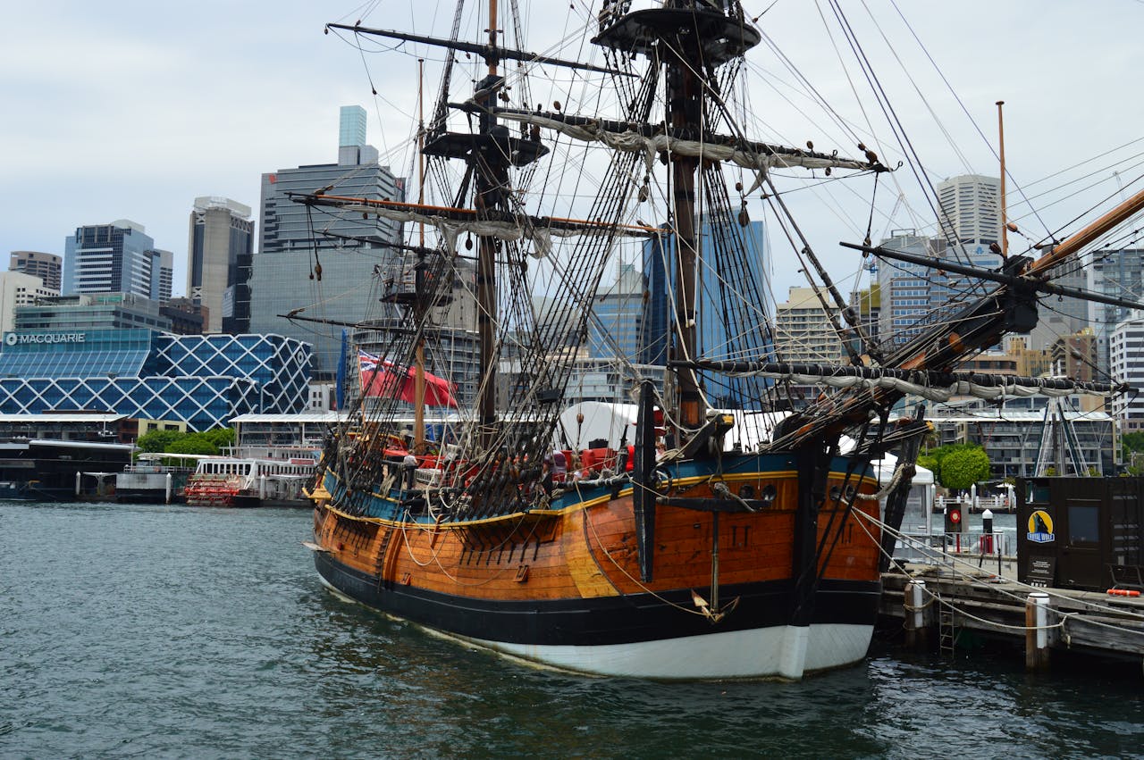 A vintage ship moored in Sydney Harbor with city skyline in the background.